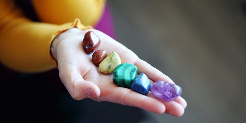 pierres et cristaux dans une main illustrant les chakras et la formation certifiante en lithothérapie